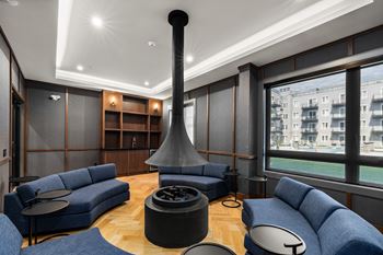A modern living room with a blue sofa set and a black fireplace.